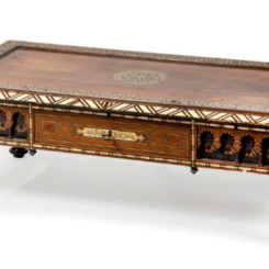 Table basse rectangulaire en bois teinté et noirci marqueté d'os et de nacre à motifs géométriques et de rosaces. La ceinture à arcatures ouvre par un tiroir en façade et deux tiroirs latéraux. Pieds fuselés. (Accidents aux pieds)<br/>Travail oriental, XXe siècle.<br/>H. 36 cm. L. 122 cm. P. 61 cm.
