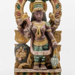 Carved wood and colored. Four-armed Durga standing on a rectangular base under an archway with Kirtimukha. A lion lying behind her. Signs of age.